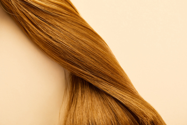 Top view of twisted brown hair on beige background - 写真・画像