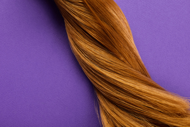 Widok z góry skręcone brązowe włosy na fioletowym tle - Zdjęcie, obraz