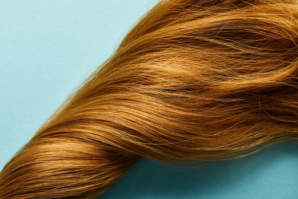Top kilátás csavart barna haj kék háttér - Fotó, kép