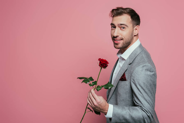 happy bearded man in suit holding red rose, isolated on pink - Фото, зображення