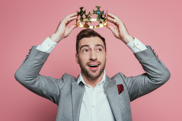 happy emotional bearded man wearing crown and suit, isolated on pink - Φωτογραφία, εικόνα