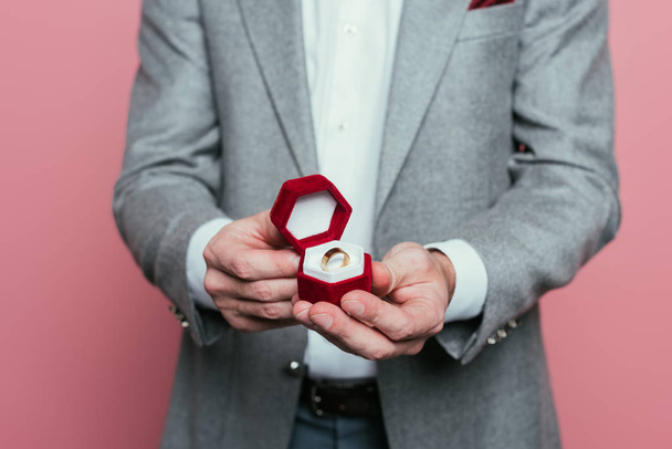 cropped view of man in suit holding box with proposal ring, isolated on pink - Фото, изображение