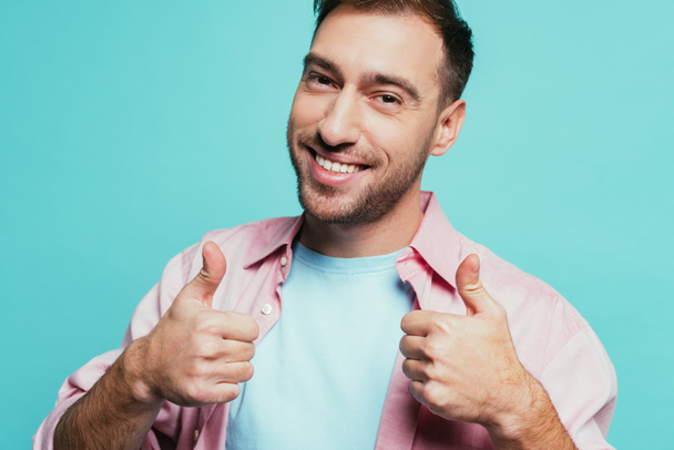 cheerful handsome man showing thumbs up, isolated on blue - Foto, imagen
