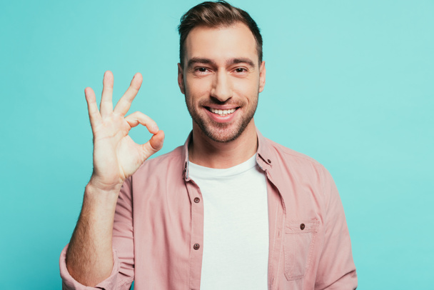 cheerful handsome man showing ok sign, isolated on blue - Photo, Image