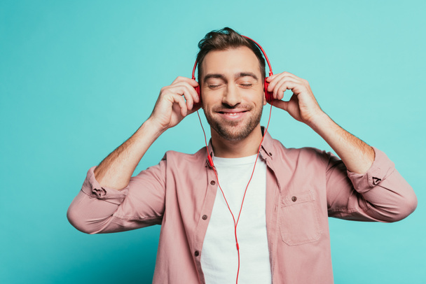 happy bearded man listening music with headphones, isolated on blue - Photo, Image