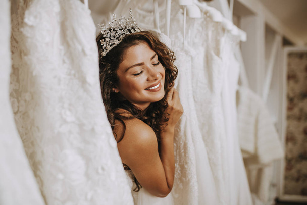 Красивая молодая женщина выбирает свадебное платье в современном свадебном салоне
. - Фото, изображение