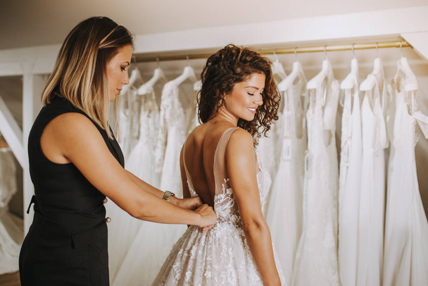 Krásná mladá brunetka žena výběru svatební šaty ve svatebním salonu. - Fotografie, Obrázek
