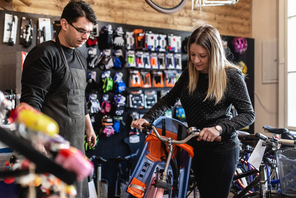 Young woman in bicycle shop choosing bike - Фото, изображение