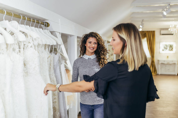 mooie jonge vrouw kiezen een bruiloft jurk in een moderne bruiloft salon. - Foto, afbeelding