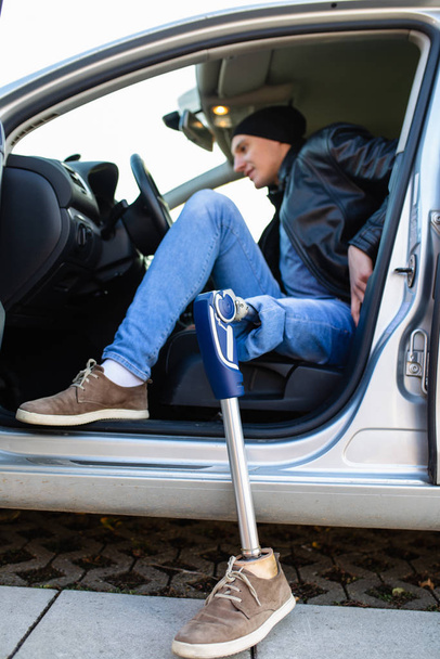 Junger Mann mit Beinprothese fährt Auto - Foto, Bild