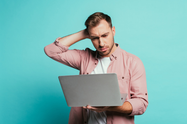 szakállas töprengő férfi laptoppal, elszigetelt kék - Fotó, kép