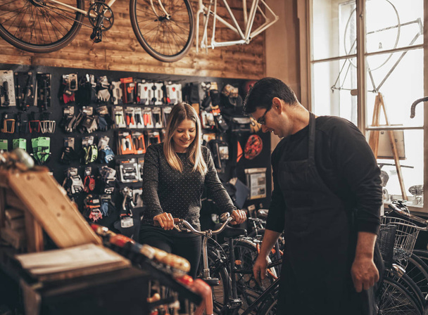 自転車屋で自転車を選ぶ若い女性 - 写真・画像