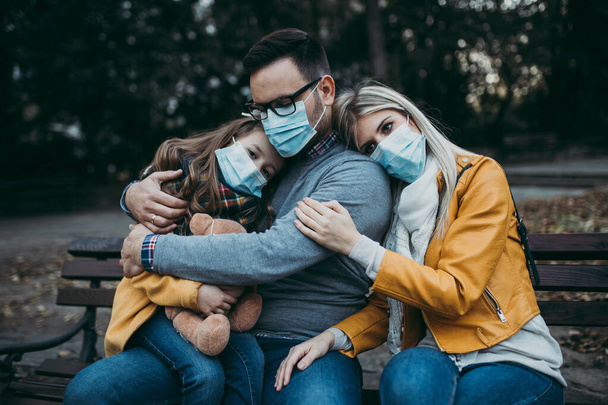 Νεαρή οικογένεια με προστατευτική μάσκα σε εξωτερικούς χώρους στο πάρκο. Έννοια της ατμοσφαιρικής ρύπανσης. - Φωτογραφία, εικόνα