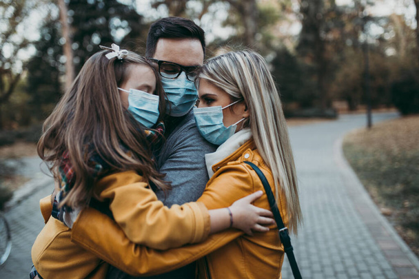 Young family in protective mask outdoors in park. Air pollution concept. - Photo, Image