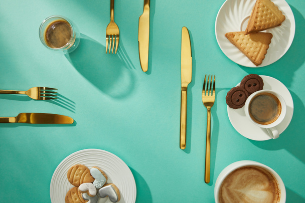 Top view of sweet cookies with coffee and golden cutlery on turquoise background - Zdjęcie, obraz
