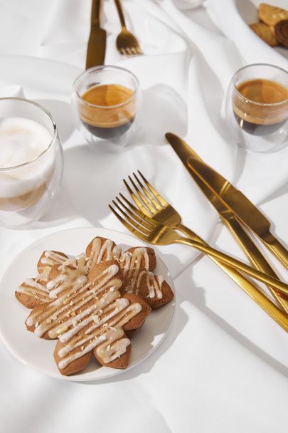Selective focus of tasty cookies with glaze and coffee on white tablecloth - Foto, Imagen