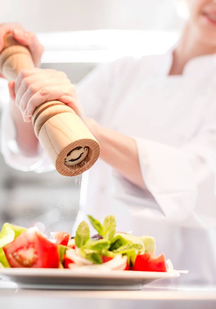Chef putting salt and pepper on salad - Fotografie, Obrázek