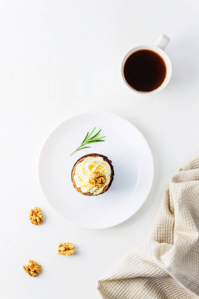 Cupcake with cream cheese, walnut, rosemary and a cup of coffee on a white table. - Foto, Imagem