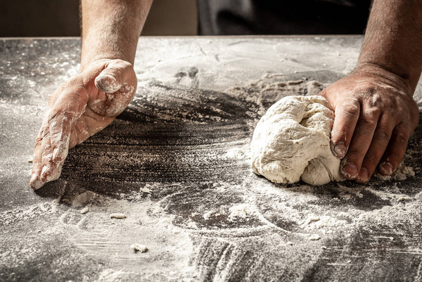 Manos masculinas haciendo masa para pizza, albóndigas o pan. Concepto de hornear. chef con masa cruda - Foto, imagen