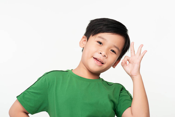 Roztomilý chlapec ukazuje ok znamení, usmívající se pozitivní, bílé studio pozadí - Fotografie, Obrázek