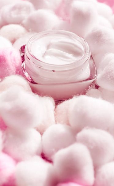 Crema viso di lusso per pelli sensibili e batuffoli di cotone rosa su ba
 - Foto, immagini
