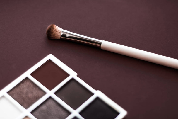 Палитра теней для век и кисть для макияжа на шоколадном фоне, глаза
 - Фото, изображение