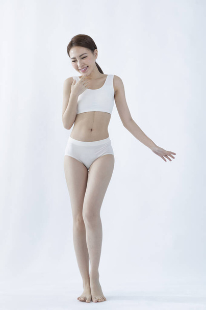 young slim woman in white underwear standing on the floor  - Zdjęcie, obraz