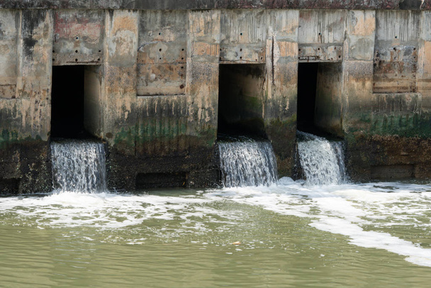 El agua sucia fluye de una tubería, tubería de aguas residuales que contamina el agua
 - Foto, Imagen