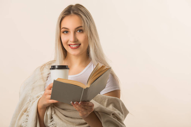 beautiful young woman is drinking coffee with a book in her hands - Photo, image