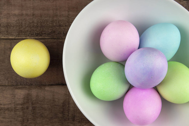 Vista aérea de huevos de Pascua pintados de pastel en un tazón blanco en r
 - Foto, Imagen
