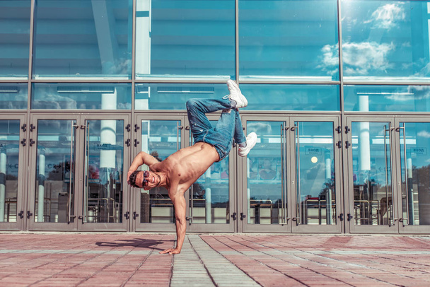 Man dancer, stand on one arm, dancing breakdance, summer in city, free space for text, hip-hop break dancer. Youth lifestyle, active, trend modern, fitness sport, positive motivation. - Photo, Image