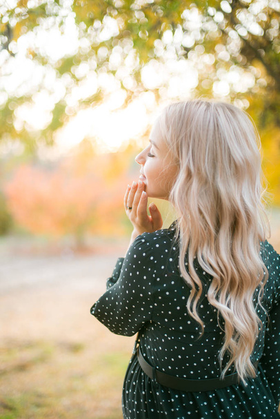 Cute pregnant woman with blond hair walks in the autumn park at sunset. Happy motherhood. Autumn pregnancy - Valokuva, kuva