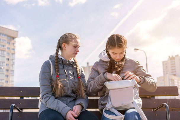 girls sit on bench on city street with backpack - Photo, image