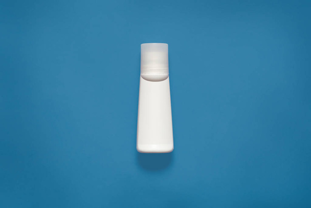 Mockup horizontal picture of white plastic bottle for liquids, cosmetic issues, situated in centre of photo, isolated over phantom blue background. Plastic concept. Copyspace for advertisement. - Zdjęcie, obraz