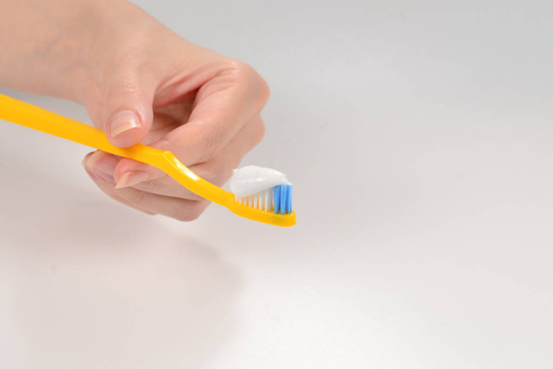 Woman holds toothbrush with toothpaste in her hand isolated on w - Photo, Image