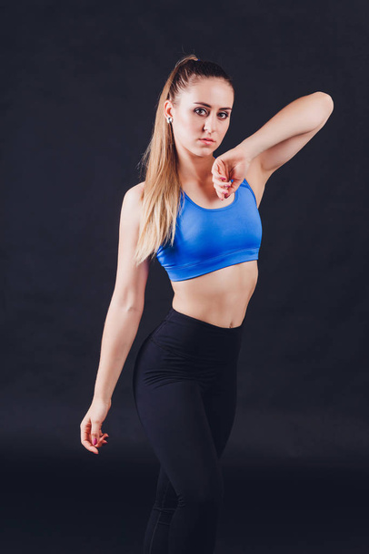 Young fitness woman with gloved hands featuring tight abdominal muscles over black background with copy space Muscular single fit woman with long blonde hair and abs Fitness people training. - Photo, Image