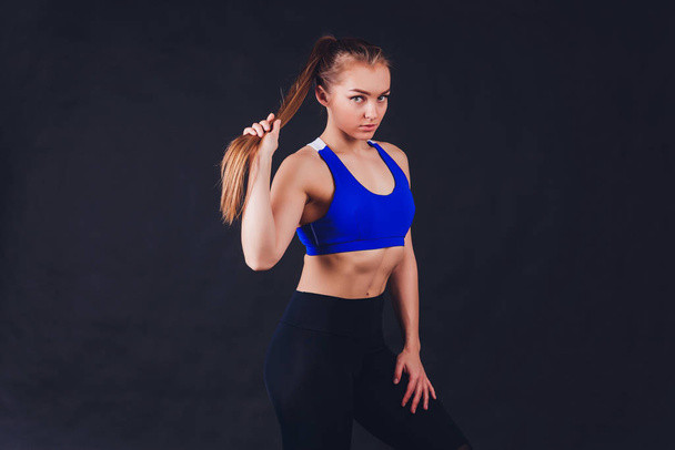 Young fitness woman with gloved hands featuring tight abdominal muscles over black background with copy space Muscular single fit woman with long blonde hair and abs Fitness people training. - Fotografie, Obrázek