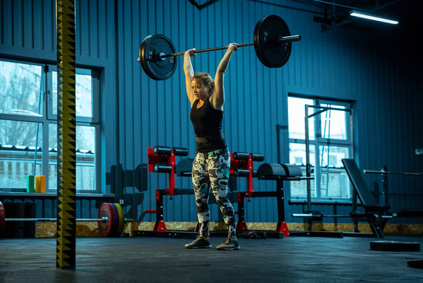 Caucasian teenage girl practicing in weightlifting in gym - Foto, imagen