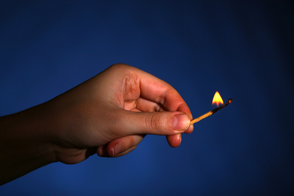 Burning match in hand on black background - Photo, image