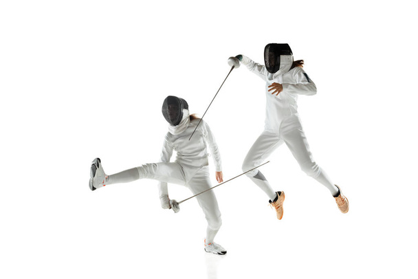 Teen girls in fencing costumes with swords in hands isolated on white background - Foto, immagini