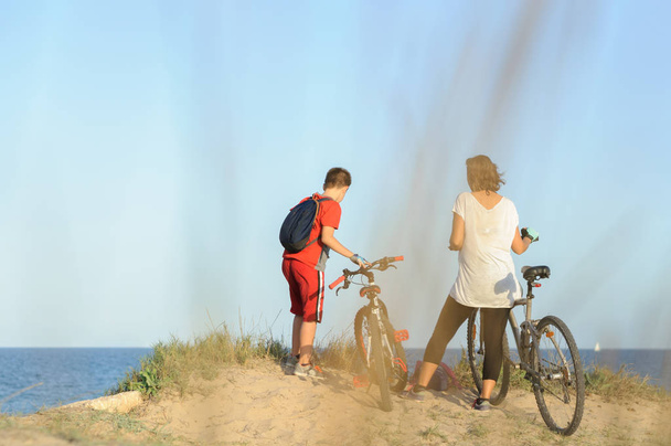 garçon et jeune femme sur un vélo sur une falaise au bord de la mer
 - Photo, image