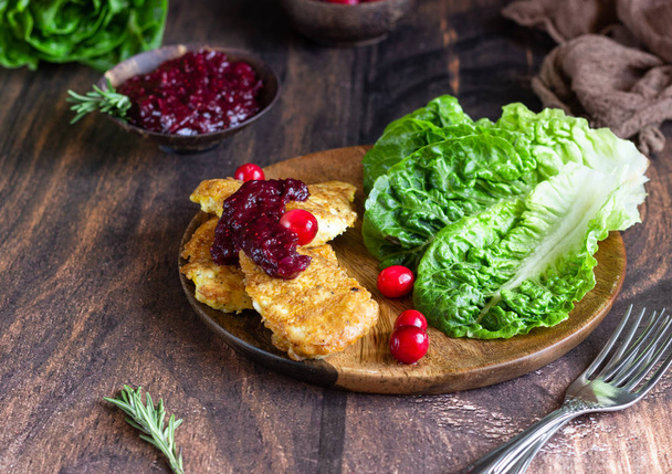 Traditional Viennese chicken schnitzel served with cranberry sauce and green salad. Wooden background. Chicken steak in breading, sauce and fresh salad.  - Foto, immagini