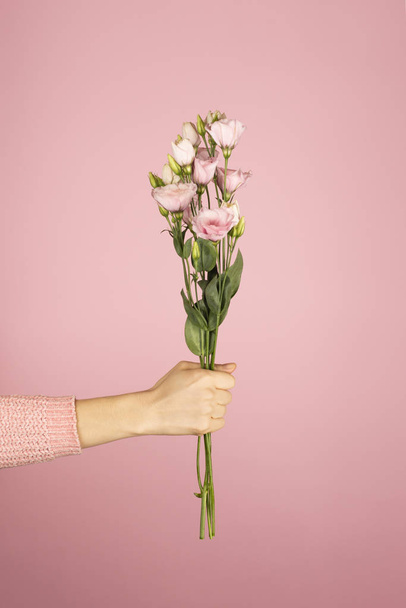 Krásná kytice růžové Eustoma v ženské ruce na růžovém pozadí. - Fotografie, Obrázek