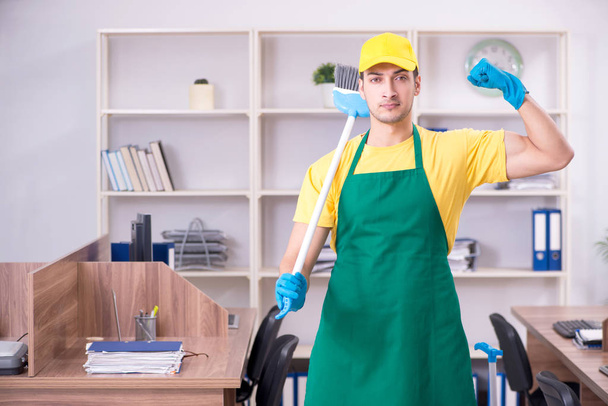 Young male contractor cleaning the office - 写真・画像