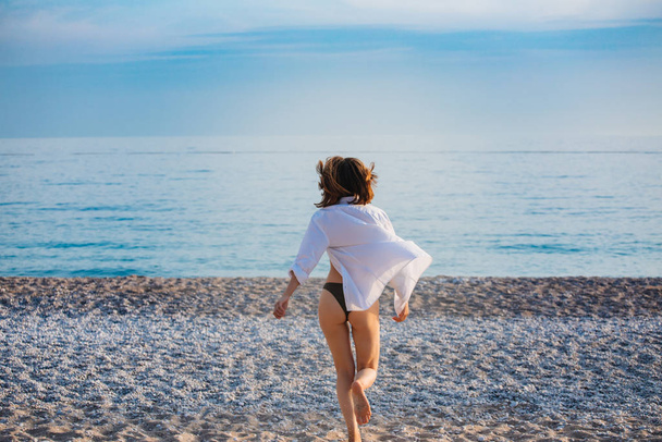 Kız denize koşuyor. Arkadan manzara. Güzel bir ganimet. Günbatımı - Fotoğraf, Görsel