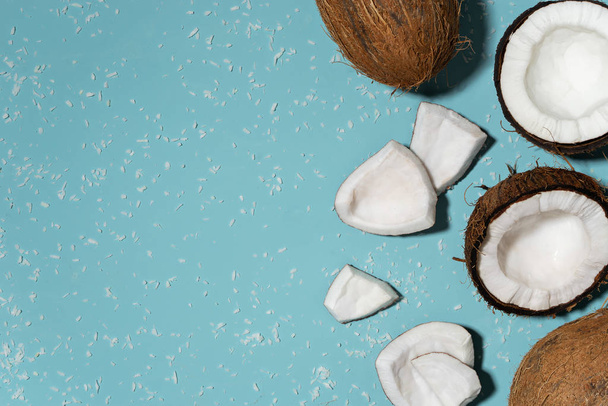 meio corte fresco e cocos inteiros com flocos de coco sobre fundo azul
  - Foto, Imagem