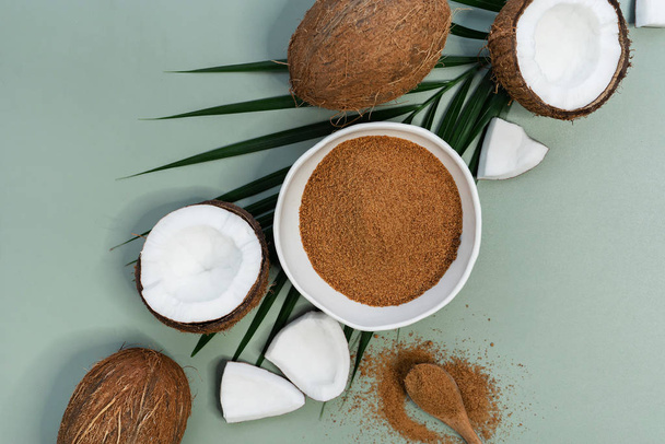 verse kokosnoten met bruine palmsuiker op groene ondergrond  - Foto, afbeelding