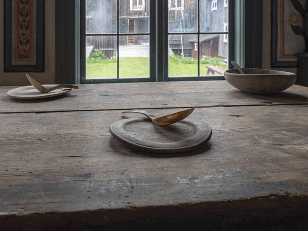 Dřevěný talíř a lžíce s kravským rohem na dřevěném stole v tmavé místnosti. - Fotografie, Obrázek