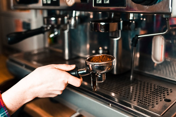 Barista φέρνει μια κάτοχος με αλεσμένο καφέ σε μια μηχανή καφέ - Φωτογραφία, εικόνα