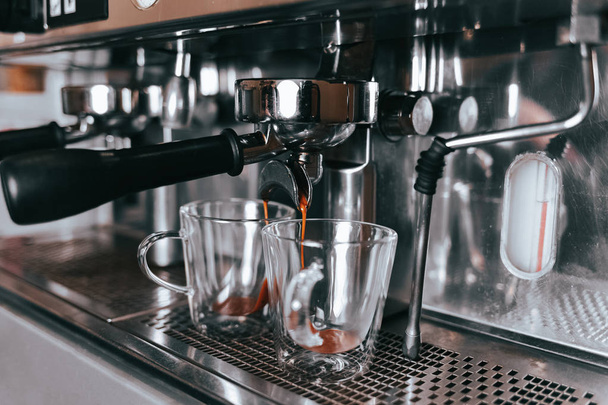  Ароматный эспрессо течет из кофеварки в чашку. Изготовление ароматного кофе с профессиональным кофейным оборудованием
 - Фото, изображение